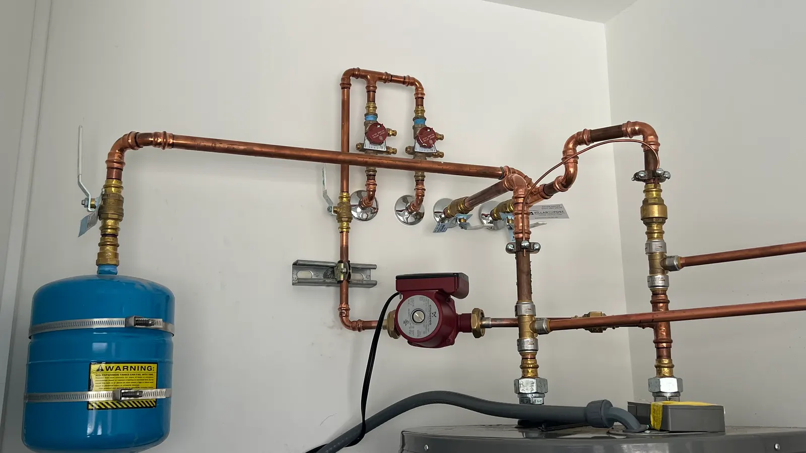 New copper piping, recirculation pump and expansion tank installed above a water heater